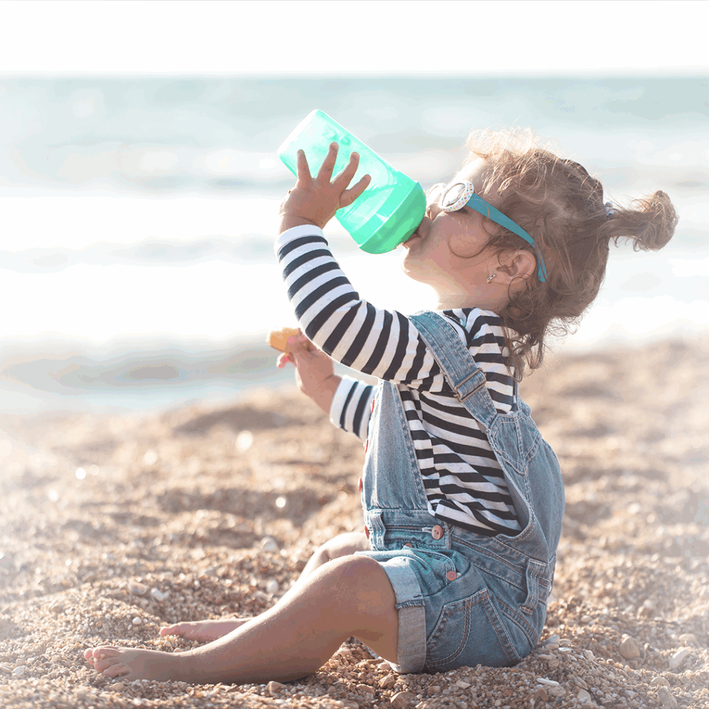 Niña tomando agua, como cuidado del calor del verano