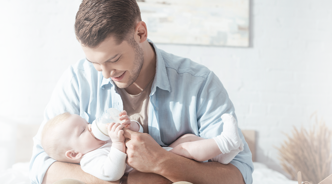 Papá alimentando con biberón a su bebé