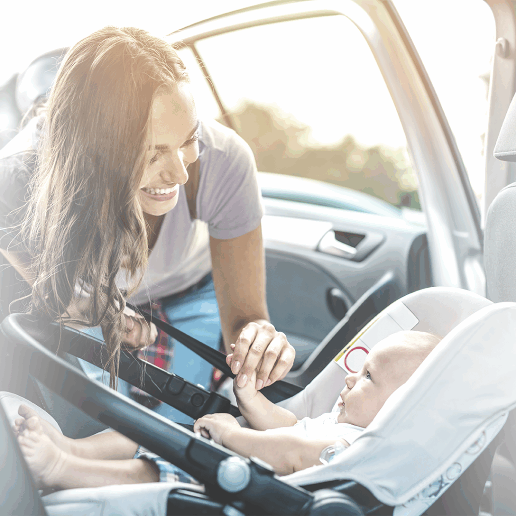 Mamá preparando a su bebé en su silla de auto.