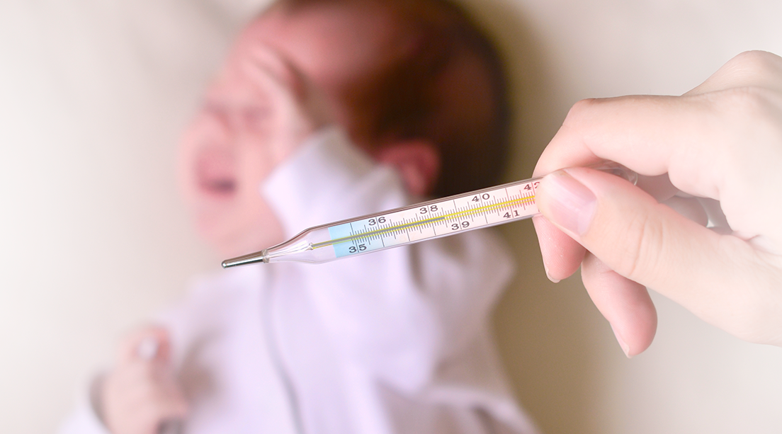 Bebé con temperatura es revisado con un termómetro.