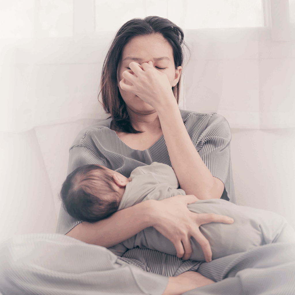 Mamá cansada, con burnout parental, carga a su bebé.